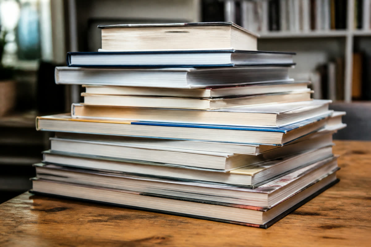 Pile de livres imprimés sur une table de travail en bois