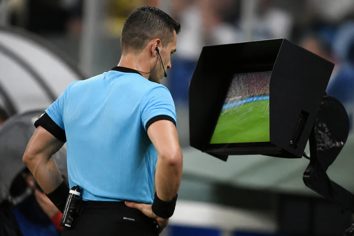 Arbitre consultant un écran de reprise vidéo sur le bord du terrain